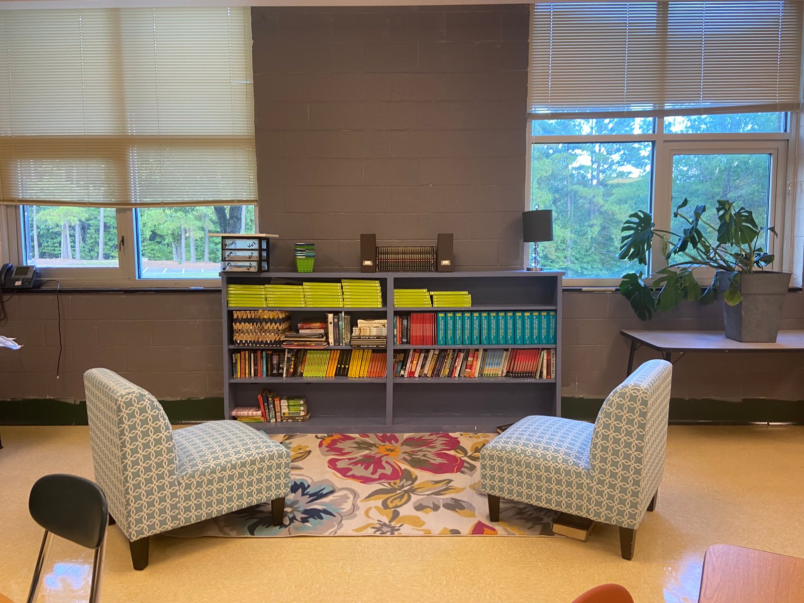 A classroom reading area with colorful chairs and organized bookshelves